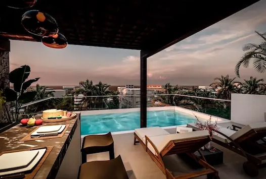 Downtown Playa del Carmen building with a rooftop pool offering panoramic sunset views, just a short walk from the beach.